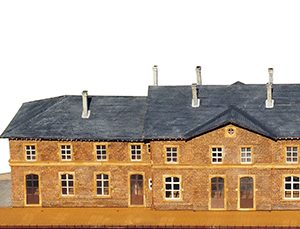 Kit GARE D'ETTELBRUCK : ce Kit représente la gare telle qu'elle était en 1926, à trois corps rattachés, sans toilettes latérales et avec des cheminées en maçonnerie.
Les fenêtres du rez-de-chaussée avaient déjà été modifiées mais portent la marque d'une arcature ancienne.
Ce Kit comprend les parquets et planchers intérieurs gravés et les cloisons avec ouvrants complèts. La toiture est en plaques d'ardoises rectangulaires en carton fort livrées en bandes avec ligne de positionnement.
L'empierrement fait l'objet d'une fine gravure en relief qui rend parfaitement l'aspect des pierres originales.
La marquise est livrée option avec le socle, référence 360-18.